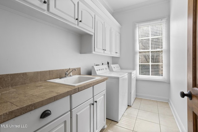 washroom with sink, light tile patterned floors, washing machine and dryer, cabinets, and ornamental molding