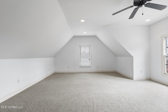 additional living space featuring vaulted ceiling, plenty of natural light, light carpet, and ceiling fan