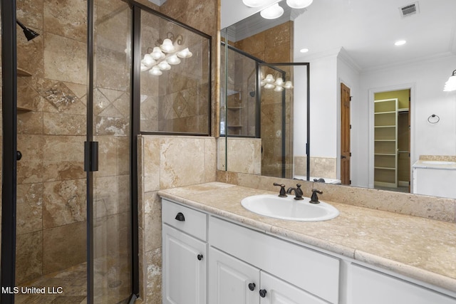 bathroom with crown molding, vanity, and a shower with shower door