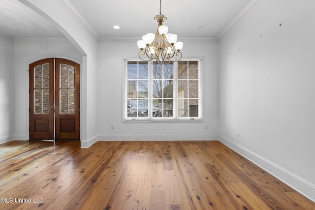 foyer entrance with hardwood / wood-style floors, crown molding, french doors, and a chandelier