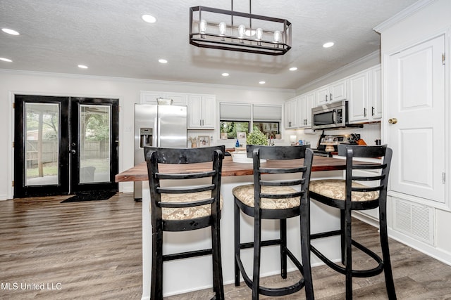 kitchen with ornamental molding, a kitchen bar, and appliances with stainless steel finishes