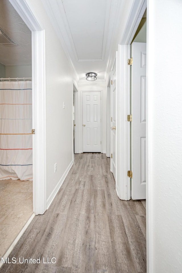 hallway featuring crown molding, visible vents, wood finished floors, and baseboards