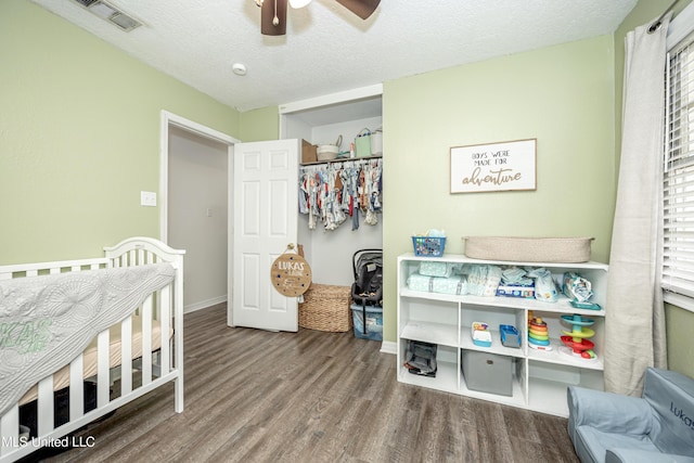 bedroom featuring wood finished floors, a textured ceiling, visible vents, ceiling fan, and baseboards