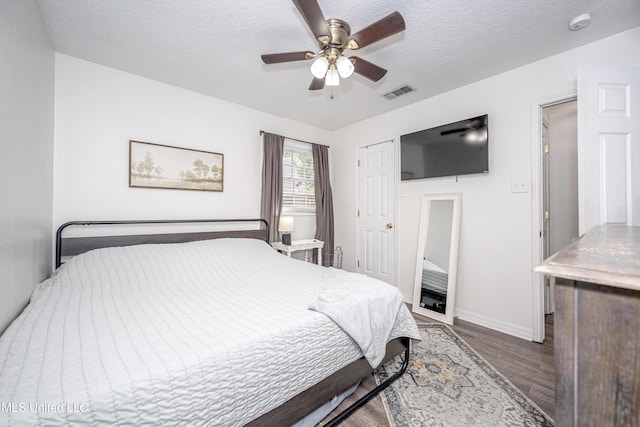 bedroom with baseboards, visible vents, a textured ceiling, and wood finished floors