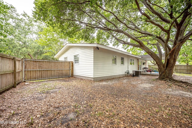 back of house featuring a fenced backyard, a gate, and central AC