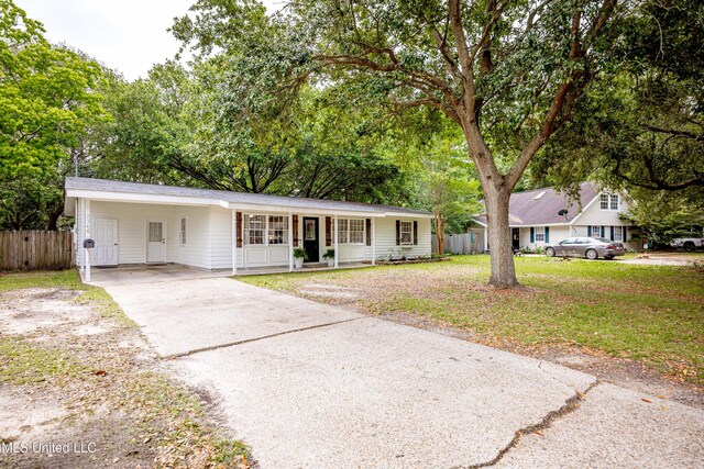 single story home with driveway, fence, covered porch, a front yard, and a carport