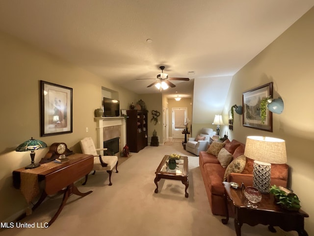 carpeted living room with ceiling fan and a tiled fireplace