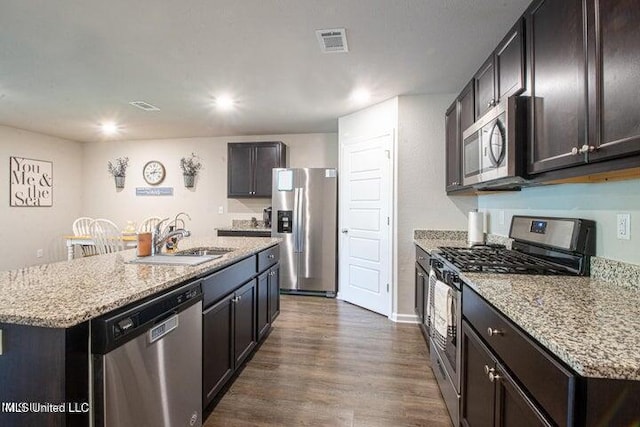 kitchen featuring stainless steel appliances, dark hardwood / wood-style flooring, sink, and a center island with sink