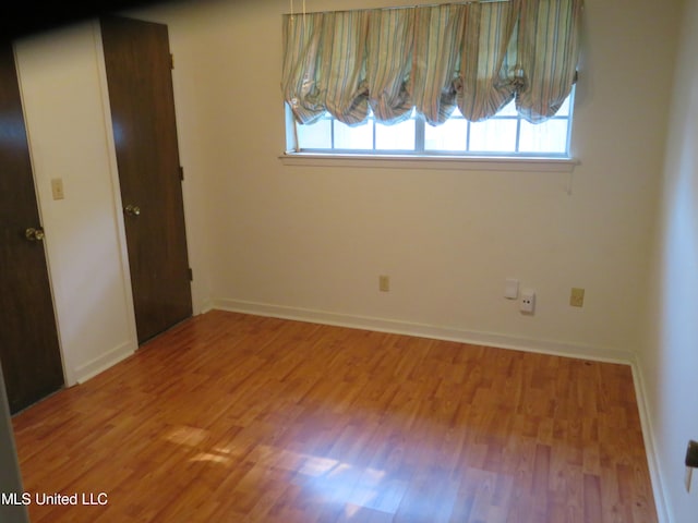 unfurnished bedroom with multiple windows and wood-type flooring