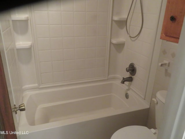 bathroom featuring toilet and tiled shower / bath