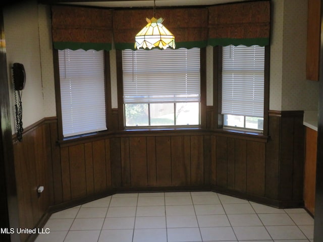 unfurnished dining area with wooden walls and light tile patterned floors