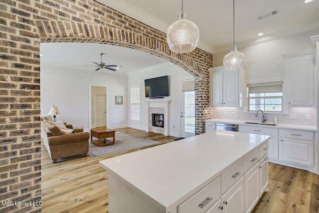 953 Glenwild Cir, Canton, MS 39046 - kitchen with light wood finished floors, ornamental molding, a ceiling fan, a fireplace, and light countertops