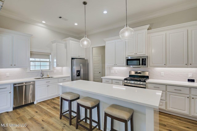 953 Glenwild Cir, Canton, MS 39046 - kitchen featuring appliances with stainless steel finishes, a breakfast bar, white cabinets, tasteful backsplash, and light wood-style floors