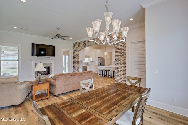 953 Glenwild Cir, Canton, MS 39046 - dining space with light wood-type flooring, ceiling fan, arched walkways, a fireplace, and ornamental molding