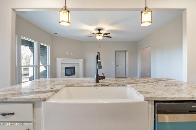 kitchen featuring decorative light fixtures, ceiling fan, sink, and a brick fireplace