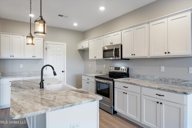 kitchen featuring white cabinetry, sink, stainless steel appliances, an island with sink, and pendant lighting