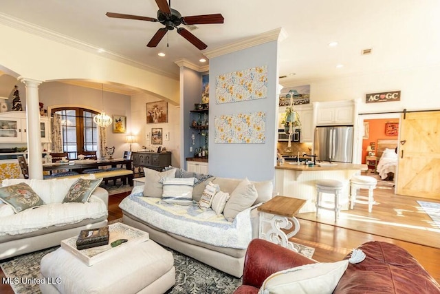 living area featuring arched walkways, decorative columns, light wood-style flooring, and a barn door