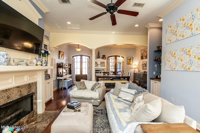 living area with arched walkways, a fireplace, crown molding, visible vents, and dark wood-type flooring