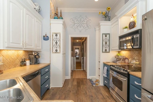 kitchen with white cabinets, stainless steel appliances, crown molding, light countertops, and blue cabinetry