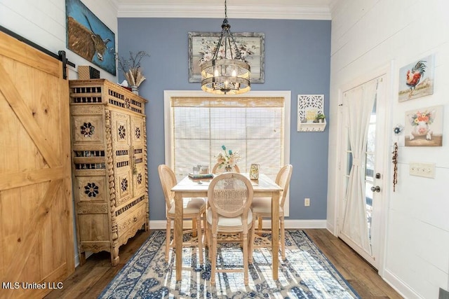 dining room featuring ornamental molding, wood finished floors, an inviting chandelier, and a barn door