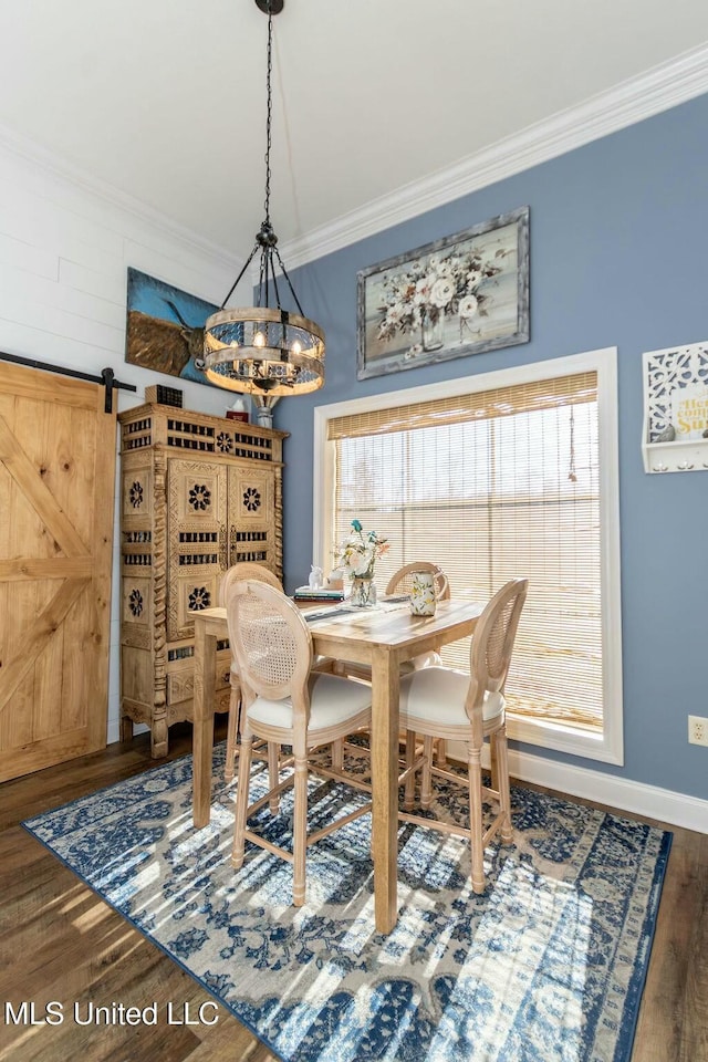 dining area with a barn door, baseboards, ornamental molding, wood finished floors, and a chandelier