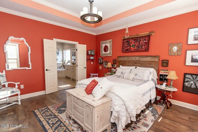 bedroom with a raised ceiling, ornamental molding, connected bathroom, wood finished floors, and baseboards