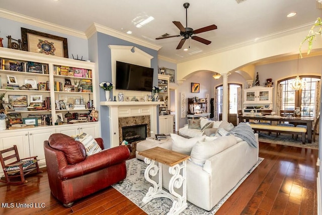 living room featuring arched walkways, dark wood-type flooring, a ceiling fan, ornamental molding, and ornate columns