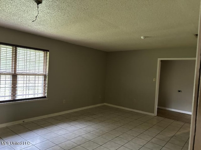 empty room featuring light tile patterned floors and a textured ceiling