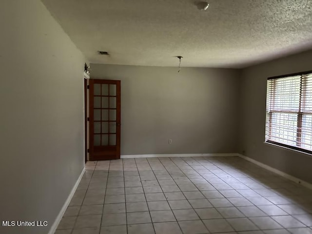 tiled spare room featuring a textured ceiling