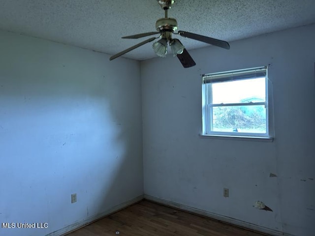 empty room with ceiling fan, wood-type flooring, and a textured ceiling