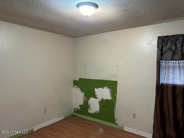 empty room with wood-type flooring and a textured ceiling