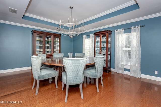 dining space featuring ornamental molding, hardwood / wood-style floors, a chandelier, and a tray ceiling