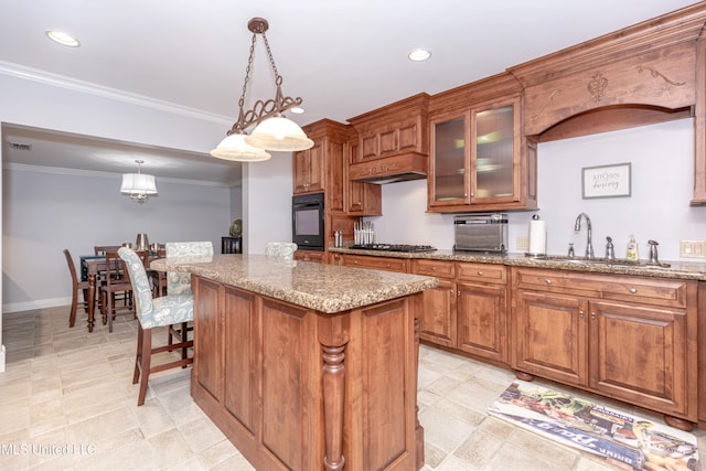 kitchen with a kitchen island, black oven, sink, decorative light fixtures, and light stone counters