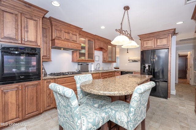 kitchen featuring light stone countertops, black appliances, sink, pendant lighting, and a center island