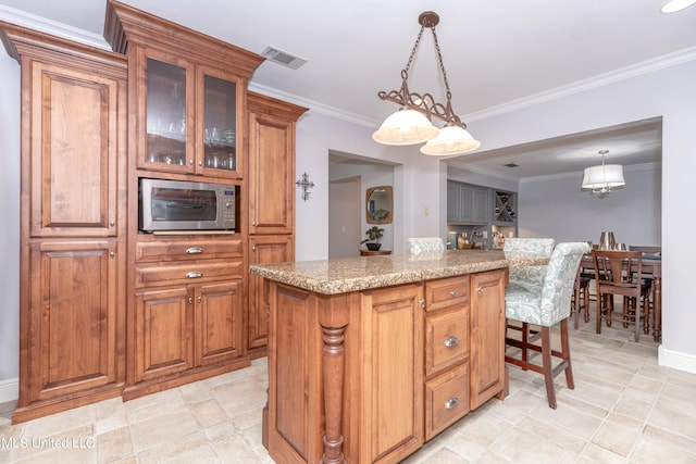 kitchen with crown molding, light stone countertops, a center island, and hanging light fixtures