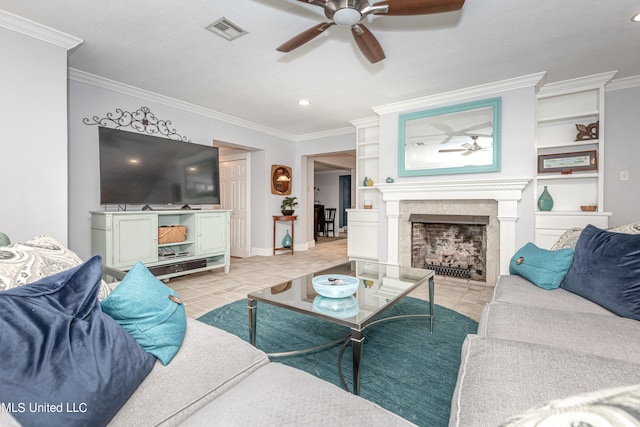 living room featuring crown molding, built in features, and a tile fireplace