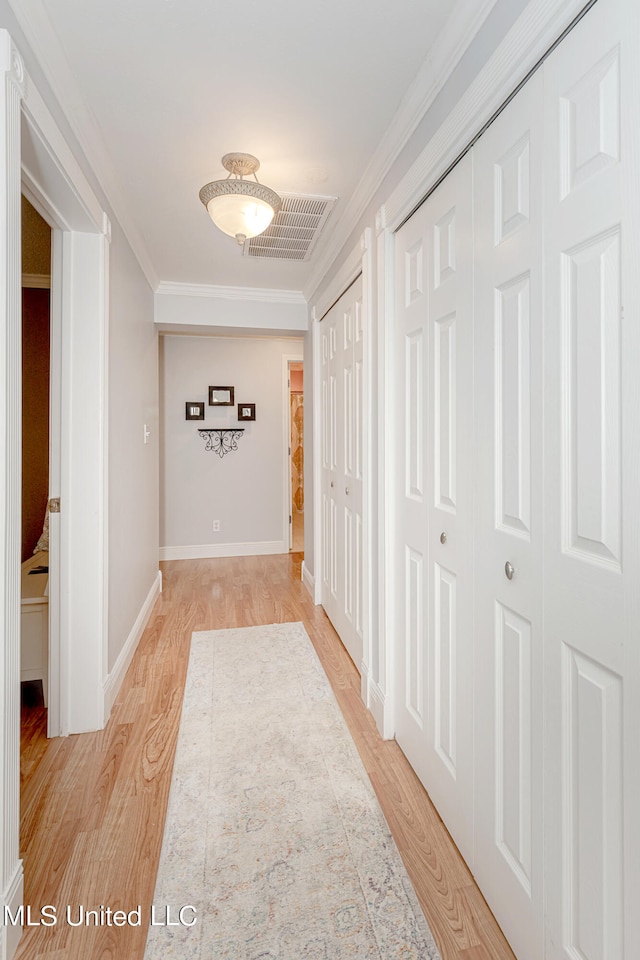 hall featuring crown molding and light hardwood / wood-style floors