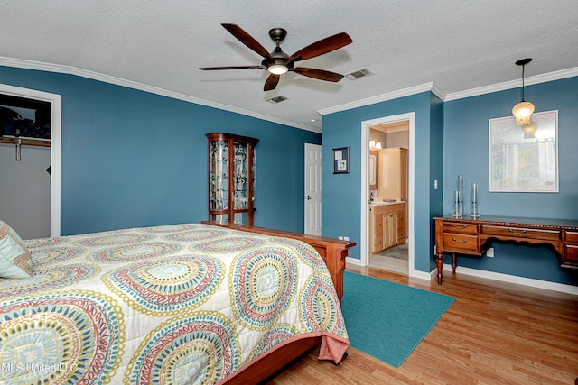 bedroom with light hardwood / wood-style flooring, a textured ceiling, ceiling fan, and crown molding