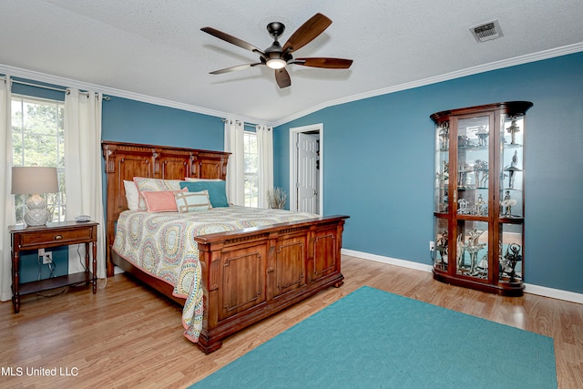 bedroom featuring ceiling fan, a textured ceiling, ornamental molding, and light hardwood / wood-style flooring