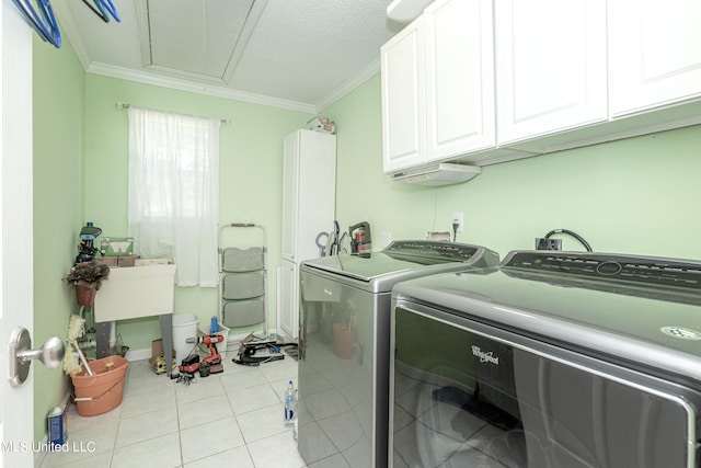 laundry area featuring crown molding, cabinets, separate washer and dryer, and light tile patterned floors