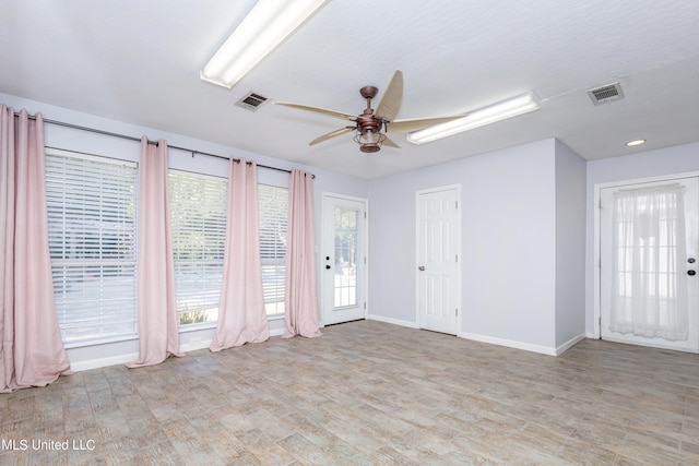 spare room with ceiling fan, a wealth of natural light, and light hardwood / wood-style floors