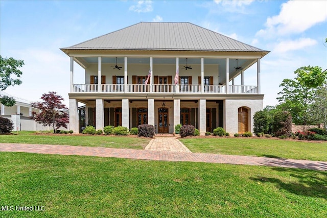 view of front facade featuring metal roof, a balcony, a ceiling fan, a standing seam roof, and a front yard