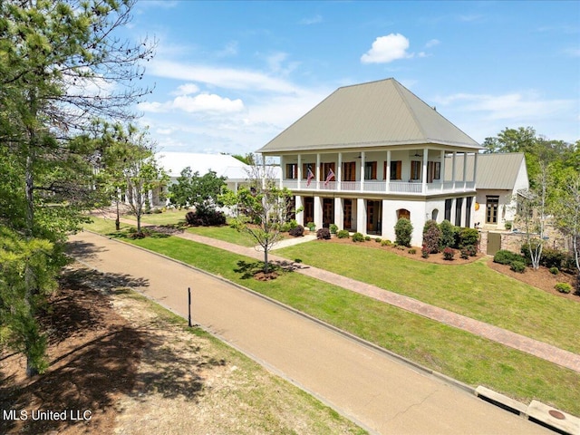 exterior space featuring a balcony, metal roof, and a lawn