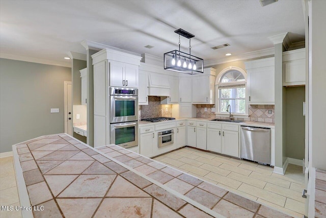 kitchen with stainless steel appliances, sink, decorative light fixtures, white cabinets, and tile counters