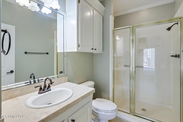 bathroom with vanity, toilet, a shower with shower door, and ornamental molding