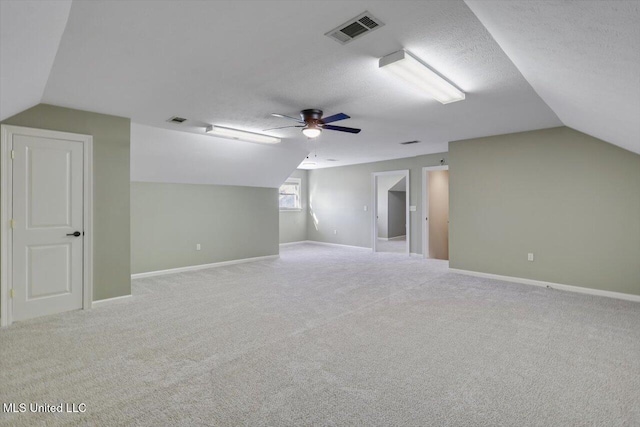 bonus room featuring lofted ceiling, ceiling fan, light carpet, and a textured ceiling