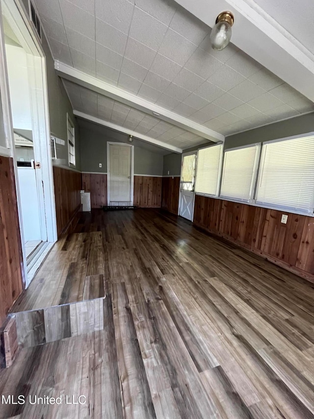 unfurnished room with wood walls, lofted ceiling, and hardwood / wood-style flooring