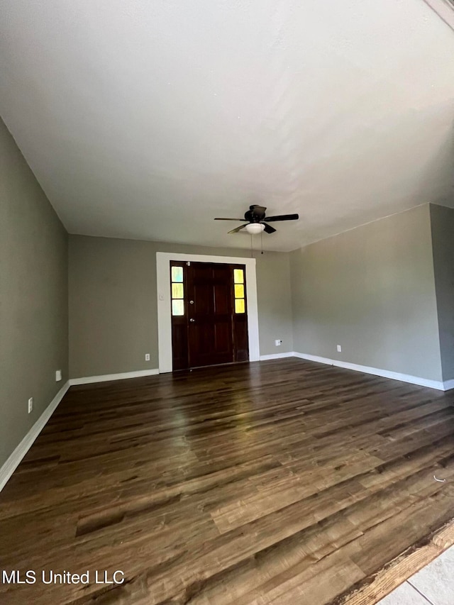 unfurnished living room featuring ceiling fan and dark wood-type flooring