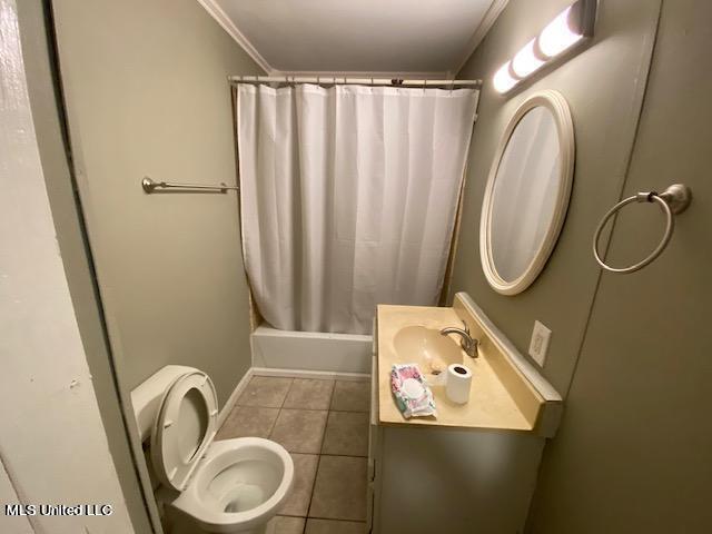 full bathroom featuring tile patterned floors, ornamental molding, vanity, shower / bath combo with shower curtain, and toilet