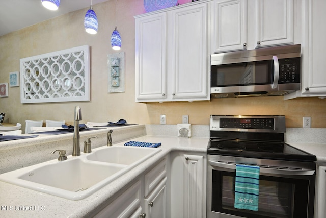 kitchen featuring appliances with stainless steel finishes, white cabinets, sink, and hanging light fixtures